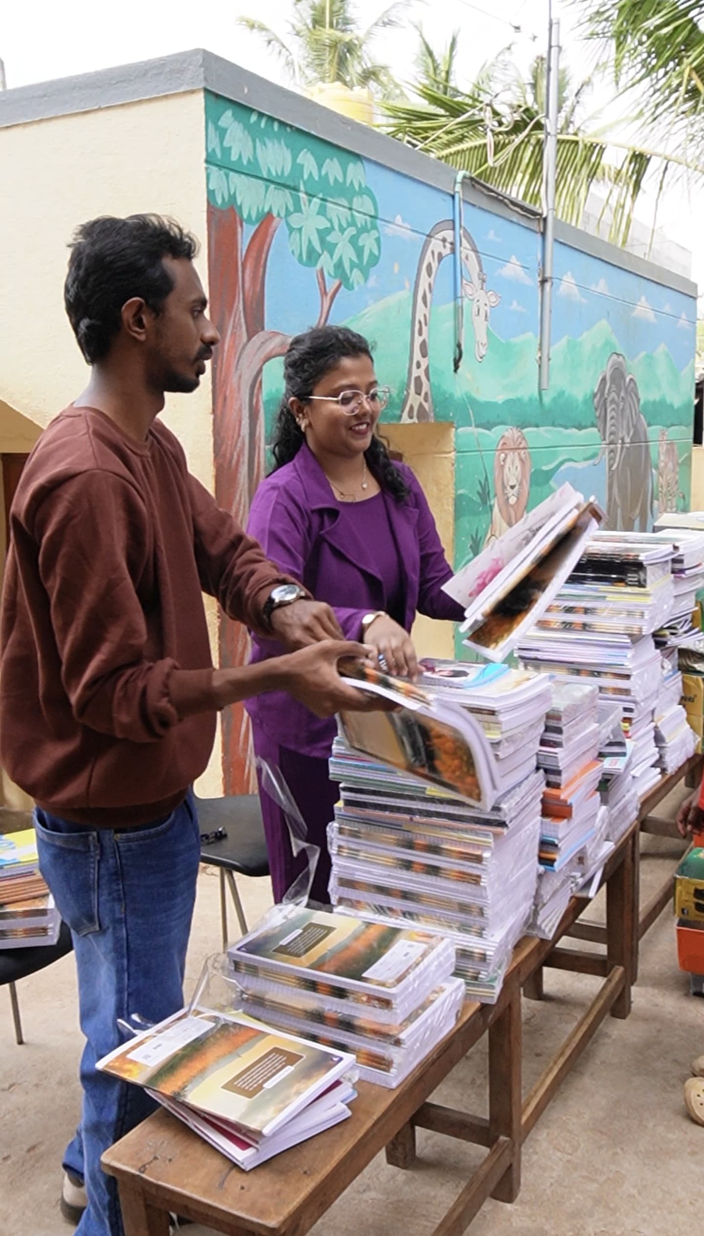 Volunteers organising stacks of notebooks and textbooks for distribution