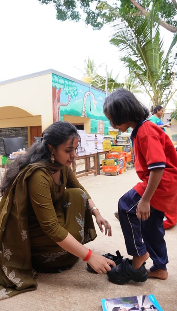 A volunteer helping a child try on new shoes